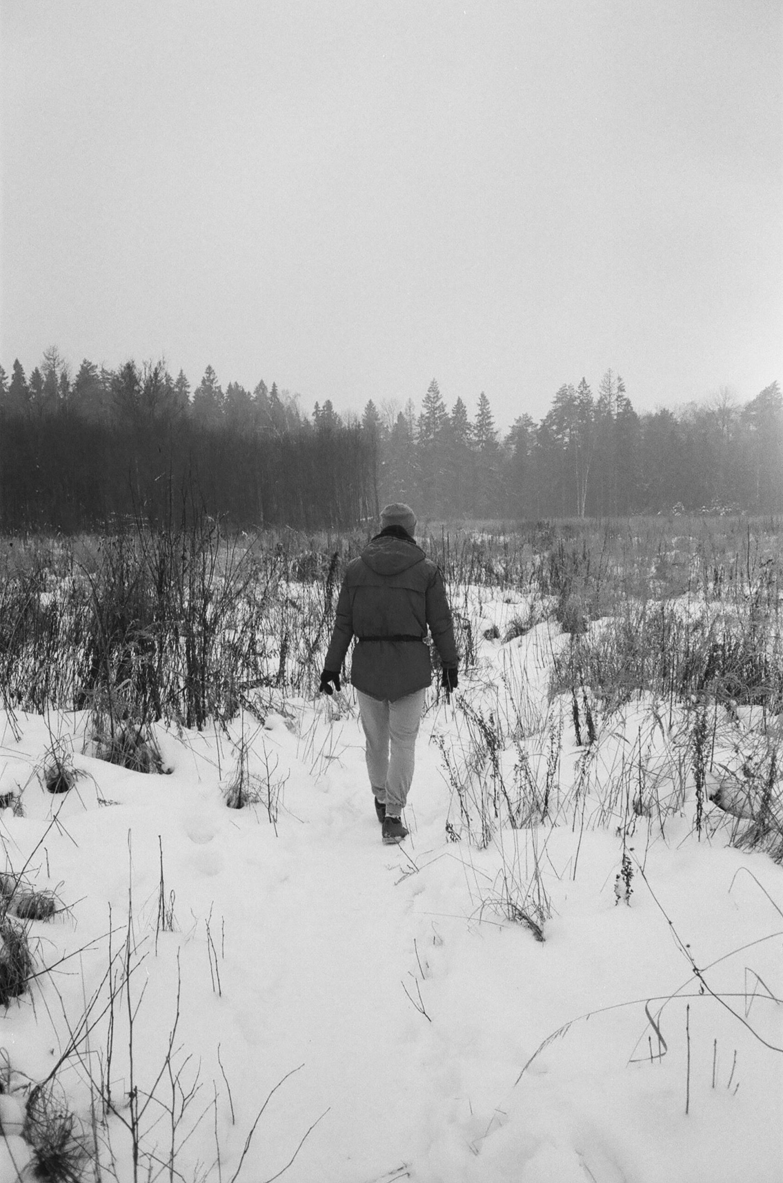 man in black jacket walking on snow covered field during daytime