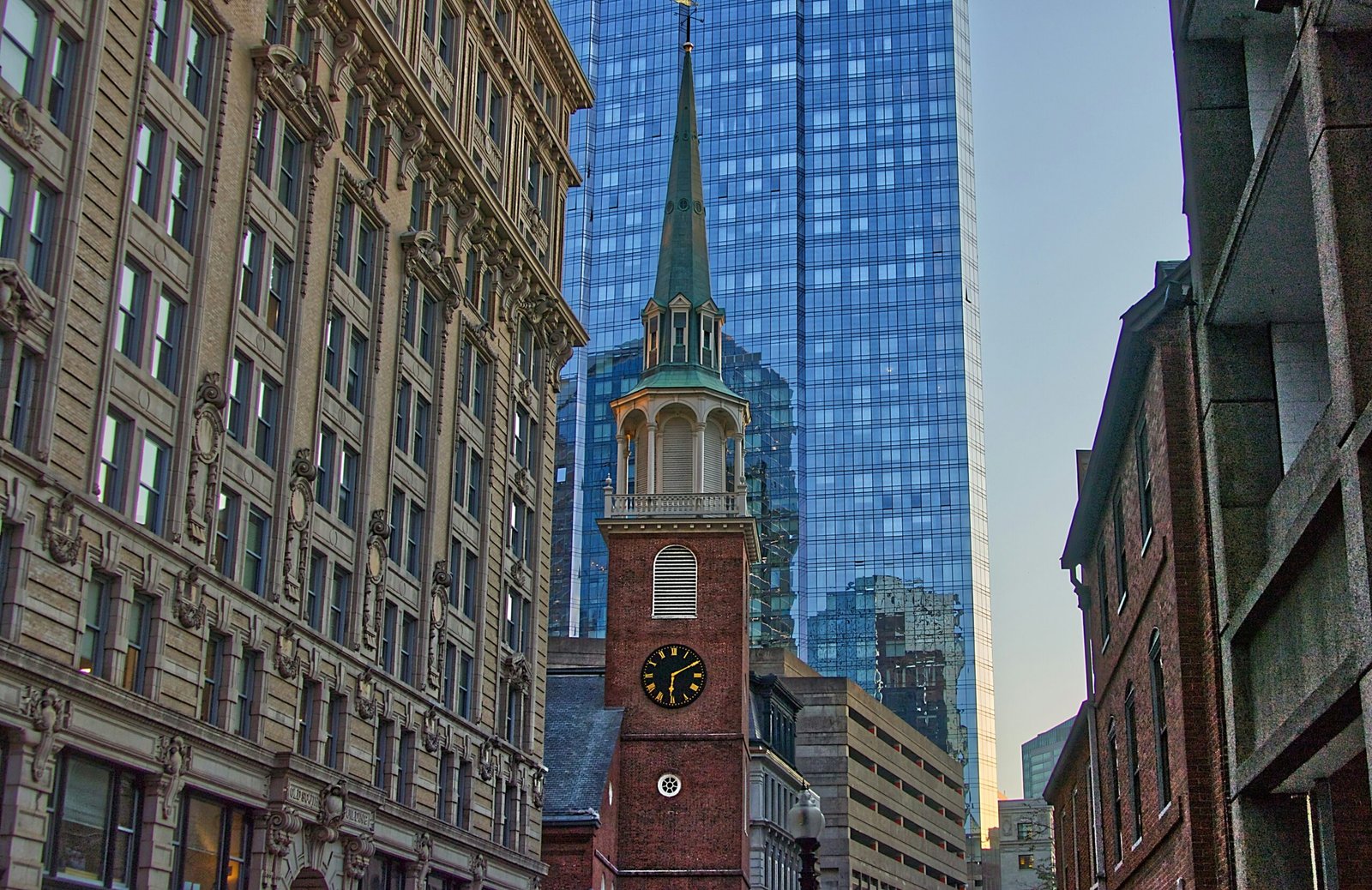 tower clock surrounded with high-rise buildings during daytime