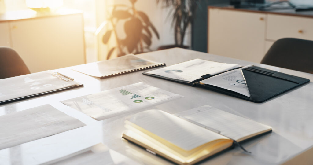 Financial documents, notebook, and pen on a desk prepared for business credit planning and budget forecasting.