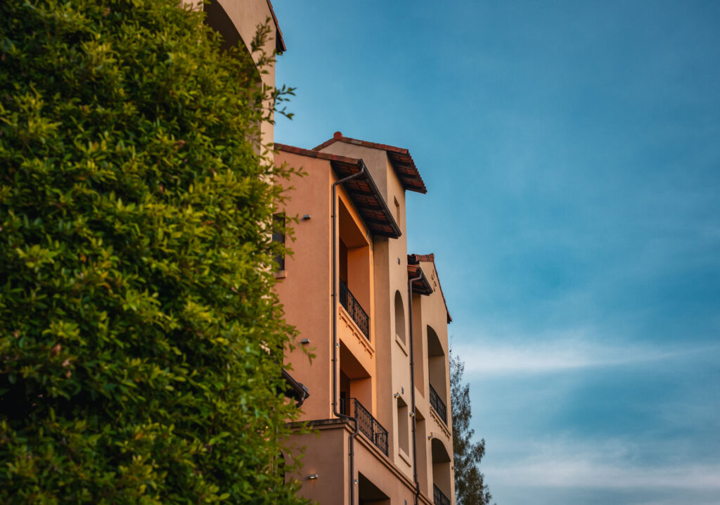 Mediterranean-style multifamily property beside mature landscaping for Senior Living Bridge Loan Considerations: Sizing, Leas
