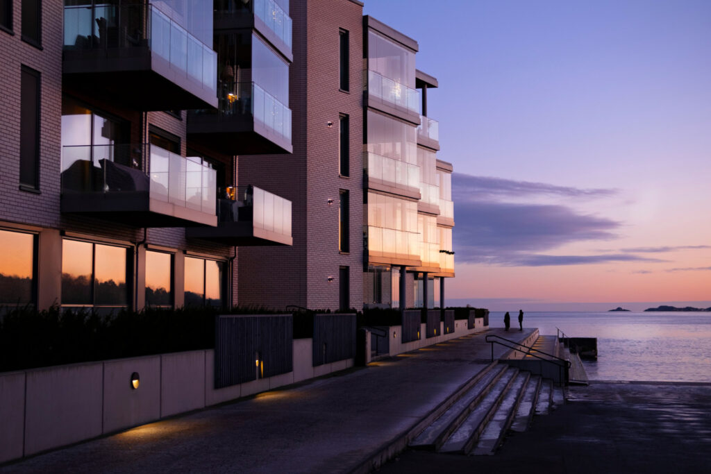 Modern waterfront apartment building with glass balconies at sunset for Structuring CRE Deals & Capital Stack | Thorne CRE