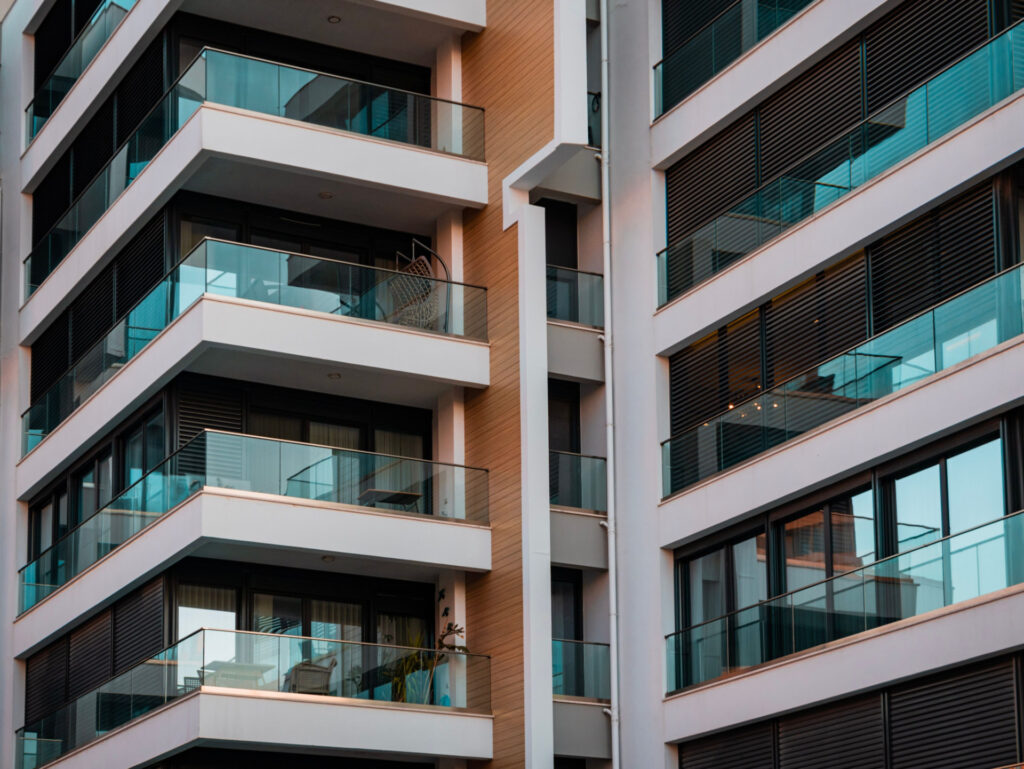 Apartment building with white balconies, glass railings and wood accents for Financing Solutions for Buying a Business Proper