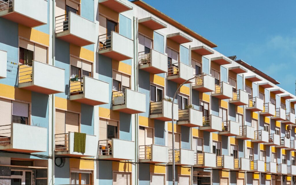 Residential building with blue and yellow panels and staggered balconies for Munni Akther | CRE & Commercial Loan Insights |