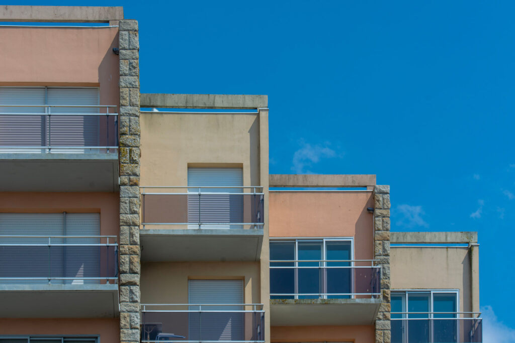 Tiered apartment building with stone-accented columns against a blue sky for Commercial Real Estate Capital Financing | Thorn