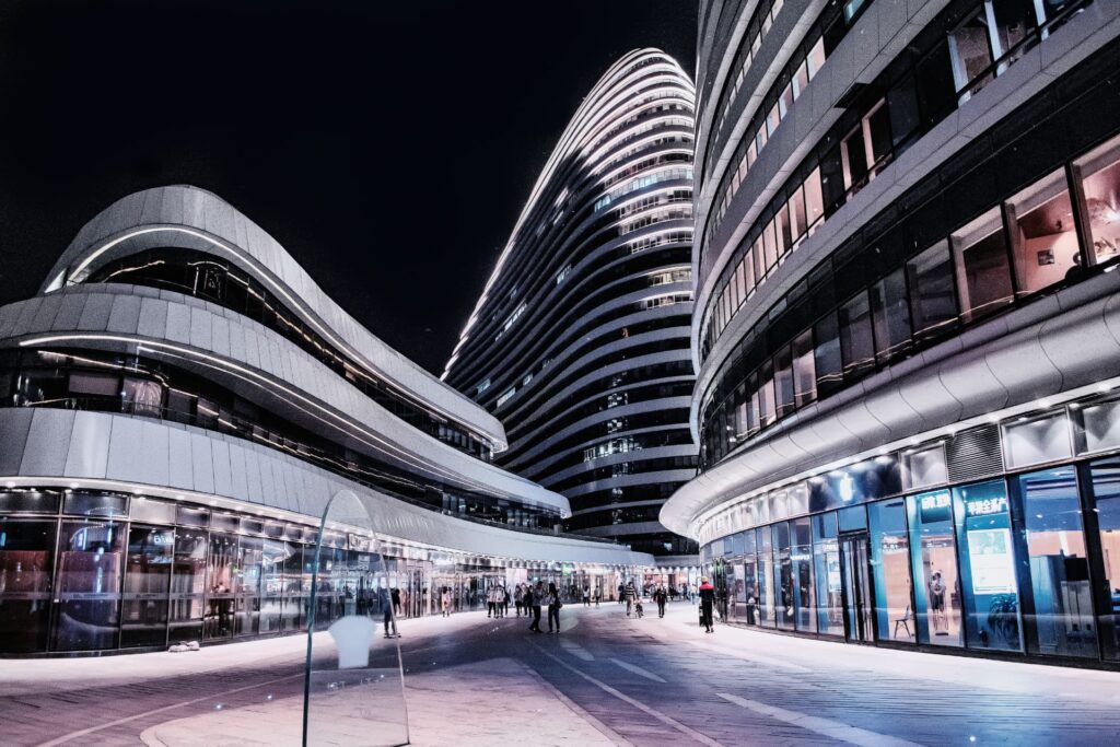 Modern curved architectural complex with a striped skyscraper at night for Reliable Commercial Loans: SBA 504 & 7(a) Guide
