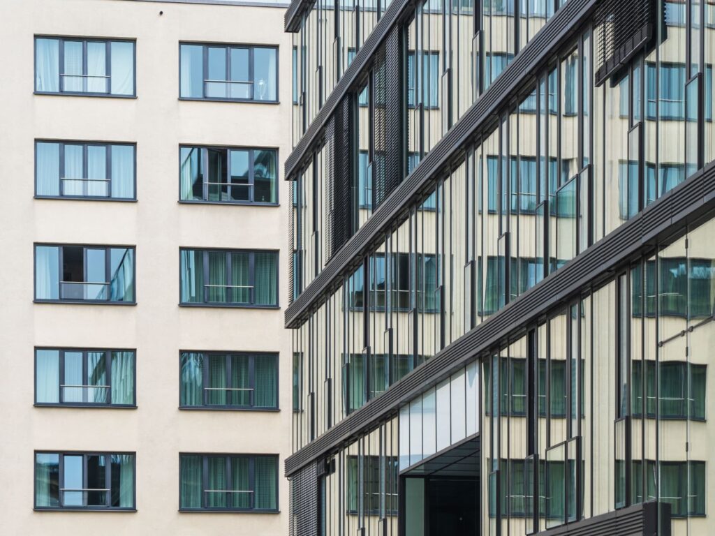 Glass office building reflecting a neighboring facade in daylight for Commercial Asset Financing & Debt Strategies | Thorne CRE