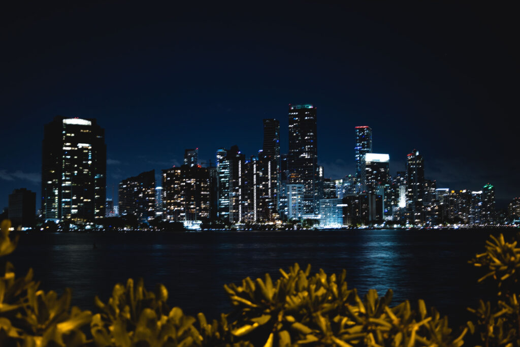 Illuminated waterfront high-rises across the water at night for Private Label Real Estate Loans vs. Wholesale CRE Financing